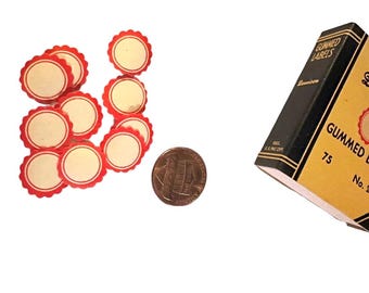 May include: A box of 75 gummed labels with a red and white scalloped edge. The labels are round and have a blank center. A penny is included for scale.