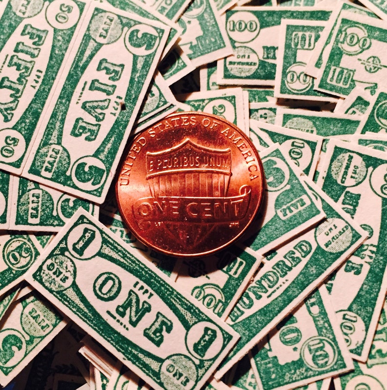 May include: A copper-colored US penny coin with the words "United States of America", "E Pluribus Unum", "One Cent", and "Liberty" inscribed on it. The coin is surrounded by a pile of green paper play money with denominations of "One", "Five", "Fifty", and "One Hundred".
