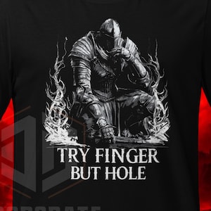 May include: Black and white graphic t-shirt featuring a knight in armour with the text "Try finger but hole".