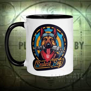 Könnte beinhalten: Eine weiße Keramiktasse mit schwarzem Rand und Henkel. Die Tasse zeigt eine farbenfrohe Illustration eines Deutschen Schäferhundes, der eine Schutzbrille trägt und einen Roboterarm im Maul hält. Der Hund trägt ein rotes Halstuch mit einem Logo, auf dem "Fallout" steht. Der Text "Bestest Boy" ist in einem Retro-Stil unter dem Hund geschrieben.