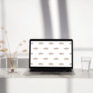 May include: A laptop computer with a white background and a repeating pattern of brown trout fish. The laptop is on a white surface with a glass of water and a vase of dried flowers.