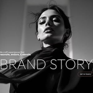 May include: Black and white image featuring a person with dark hair and makeup. The text "BRAND STORY" is prominently displayed in white, with the phrase "We craft experiences that resonate, endure, & elevate" above it. A button reads "GET IN TOUCH".