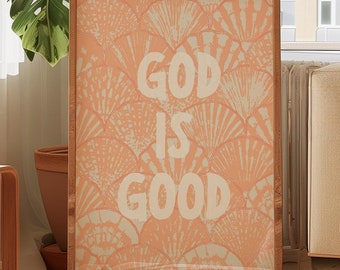 Puede incluir: Una impresión enmarcada con un fondo melocotón y un diseño blanco de hojas estilizadas. El texto "GOD IS GOOD" está impreso en blanco en la impresión.