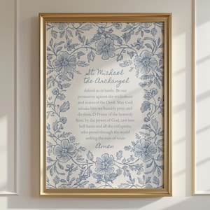 May include: Framed print featuring the prayer to St. Michael the Archangel. The text is surrounded by a blue floral border on a cream background. The frame is gold-colored.