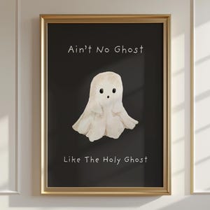 Può includere: Una stampa artistica incorniciata con una cornice dorata. L'opera presenta un'illustrazione ad acquerello di un simpatico fantasma bianco su sfondo nero. Il testo "Ain't No Ghost Like The Holy Ghost" è scritto sopra e sotto il fantasma.