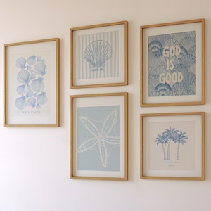 Peut inclure: Cinq impressions encadrées sur un mur blanc. Les impressions présentent des illustrations bleues et blanches de coquillages, une étoile de mer, des palmiers et le texte "Dieu est bon".