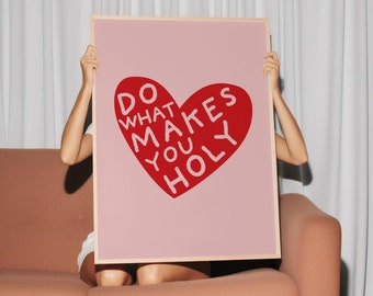 May include: A pink poster with a red heart shape that says "Do what makes you holy". The poster is being held up by a person.