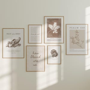 Op de afbeelding: Een verzameling ingelijste kunstprints met botanische en op de Schrift geïnspireerde ontwerpen. De prints tonen illustraties van een hoorn des overvloeds, eikenbladeren en een plant, samen met tekst waaronder "Fruit of the Spirit" en "Psalm 100". De frames zijn lichtbruin.