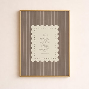 May include: Framed print with a gold-colored frame. The print features a light beige background with the words "His mercies are new every morning" in a handwritten font. The background has a brown and white striped pattern.