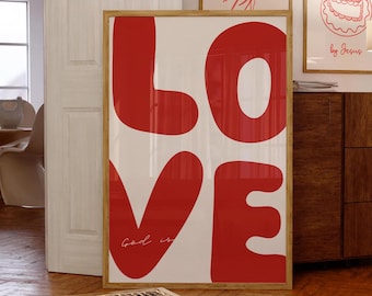 May include: A framed print with the word "LOVE" in large, red, stylized letters. The letters are outlined in white and the background is white. The text "Good is" is written in cursive in the lower left corner of the print.