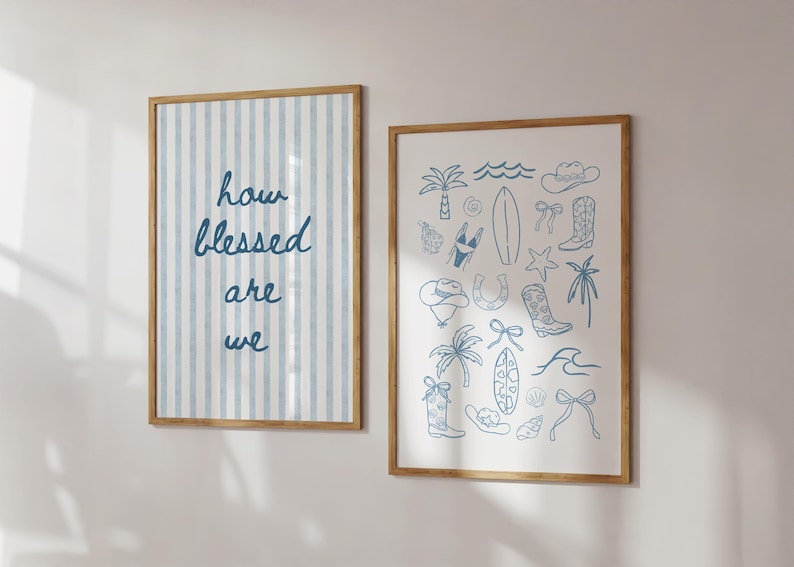 May include: Two framed prints with wooden frames on a wall. One has blue vertical stripes and the text "how blessed are we." The other print has blue line drawings of beach and western themed items.