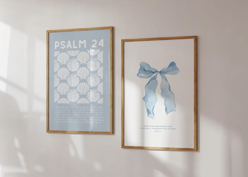 May include: Two framed art prints. One features the text "PSALM 24" above a pattern of white seashells on a light blue background. The other print displays a watercolour image of a blue bow. Both are in wooden frames.