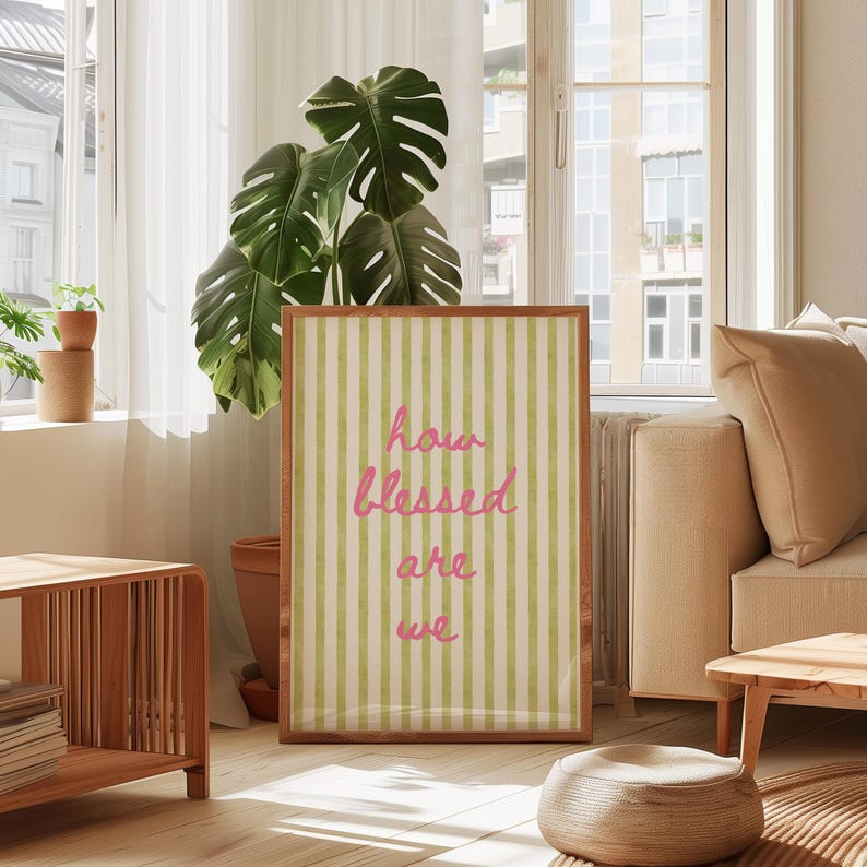 K&ouml;nnte beinhalten: Ein gerahmter Druck mit einem gr&uuml;n-wei&szlig; gestreiften Hintergrund und dem Text "how blessed are we" in rosa.