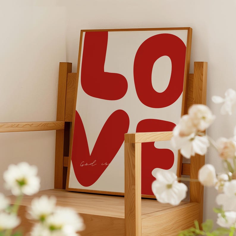 May include: A framed print with the word "LOVE" in large, red, stylized letters. The word "God is" is written in cursive below the letters.