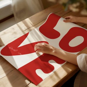 May include: A white poster with red abstract shapes and the text "Good is" written in cursive.