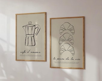 May include: Two framed prints with black line drawings. The left print features a coffee pot with the text "cafe d'amour". The right print features three croissants stacked on top of each other with the text "le pain de la vie".