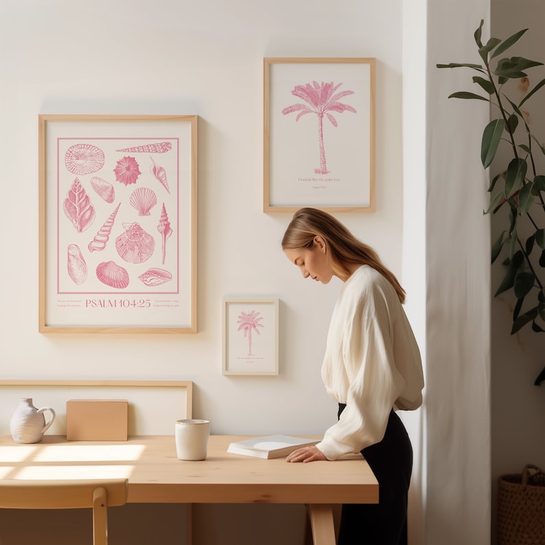 Puede incluir: Una impresi&oacute;n enmarcada con una ilustraci&oacute;n rosa de conchas marinas y el texto "PSALM 104:25". La impresi&oacute;n est&aacute; colgada en una pared blanca junto a una impresi&oacute;n enmarcada con una ilustraci&oacute;n rosa de una palmera y el texto "Gracias por la palmera".