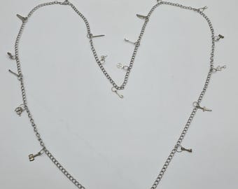 May include: A silver chain necklace with multiple charms, including keys, a hammer, a knife, and a bottle opener.