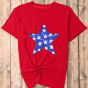 May include: Red short-sleeved t-shirt with a blue star print. The star is filled with smaller white stars.