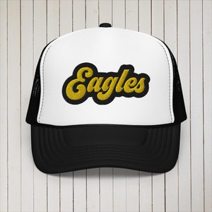 May include: A white and black trucker hat with a yellow embroidered patch that says "Eagles".