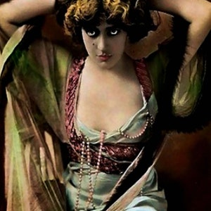 May include: Vintage-style portrait of a person in a flowing, light blue dress with a burgundy bodice and a pearl necklace. The person has dark hair and is wearing a sheer, green shawl. The image has a sepia tone.