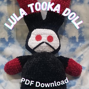 Puede incluir: Juguete de peluche de conejo de crochet negro y rojo con cara blanca y ojos de botón rojos. El juguete está etiquetado como "Lula Tooka Doll" y "PDF Download".