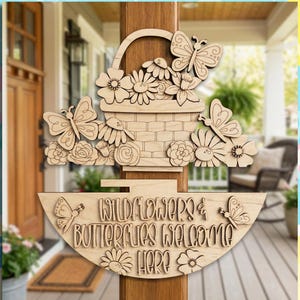 May include: A wooden welcome sign with a basket of flowers and butterflies. The sign says "Wildflowers & Butterflies Welcome Here". The sign is made of light-coloured wood and is designed for outdoor use. The sign is a decorative item.