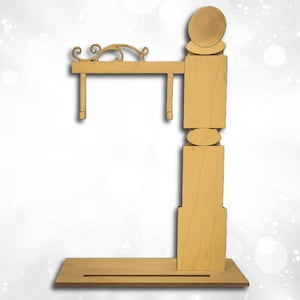 May include: A wooden sign holder with a natural finish. The sign holder has a rectangular base, a vertical support with decorative cutouts, and a horizontal arm with two hanging supports. The top of the sign holder has a decorative scroll design.
