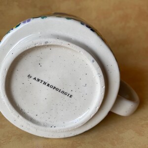 May include: A set of three ceramic mugs with a speckled, matte finish. The mugs are in shades of cream, light gray, and dark gray. Each mug has a simple, minimalist design and a rounded handle.
