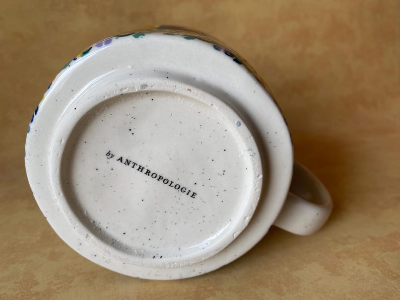 May include: A set of three ceramic mugs with a speckled, matte finish. The mugs are in shades of cream, light gray, and dark gray. Each mug has a simple, minimalist design and a rounded handle.