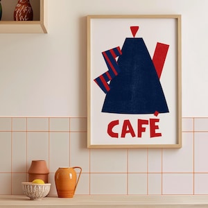 Puede incluir: Una impresión enmarcada con un diseño geométrico rojo, azul y blanco. La impresión dice "Cafe" en letras rojas.