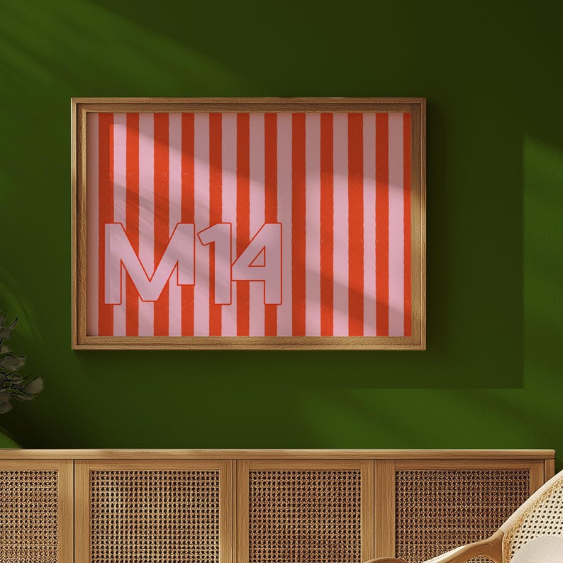 Puede incluir: Obra de arte enmarcada con un patr&oacute;n de rayas verticales en rosa y rojo. El texto "M14" se muestra en una fuente rosa claro. La obra de arte est&aacute; encerrada en un marco de madera. La obra de arte se muestra en una pared verde.