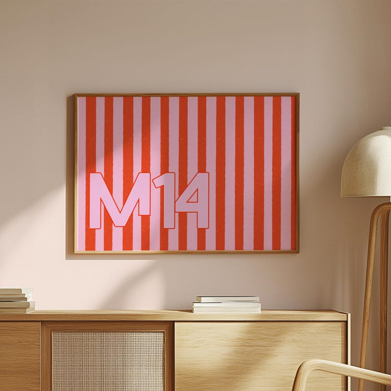 Puede incluir: Obra de arte enmarcada con un vibrante patr&oacute;n de rayas verticales rojas y rosas. El texto en negrita "M14" est&aacute; centrado en un tono rojo a juego. La obra est&aacute; encerrada en un marco de madera, a&ntilde;adiendo un toque de calidez al dise&ntilde;o moderno.