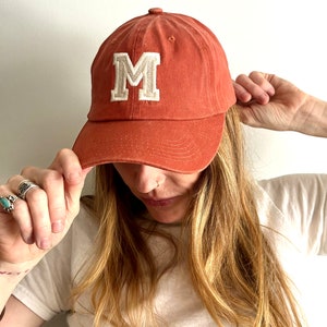 May include: A white ceramic mug with a black handle and the text "But first, coffee" in a black, handwritten-style font. The mug is on a white surface.