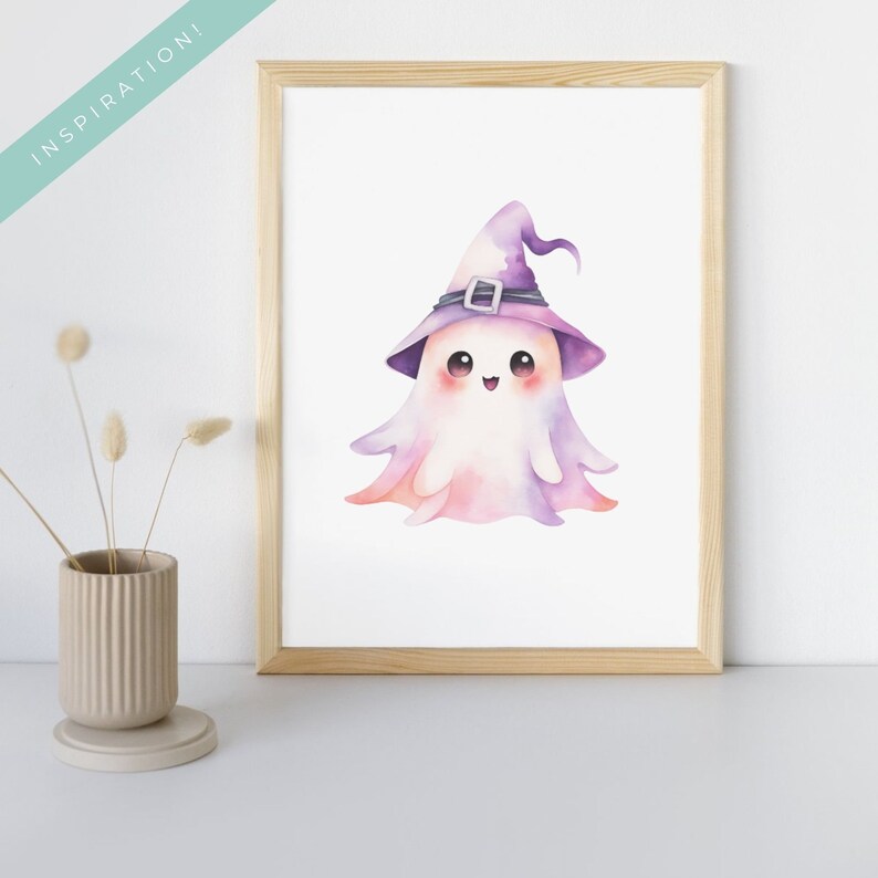 May include: A framed watercolor print featuring a cute ghost wearing a purple witch hat with a silver buckle. The ghost has a smiling face and a soft, pastel color palette of pink, purple, and white. The word "INSPIRATION!" is in the upper left corner.