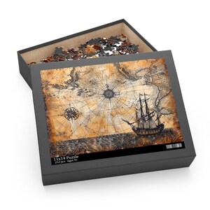 Puede incluir: Un rompecabezas de 252 piezas que presenta un mapa antiguo con un barco navegando en el océano. La caja del rompecabezas es negra con el texto "11x14 Puzzle 252 pcs Ages 9+" impreso en la parte delantera.