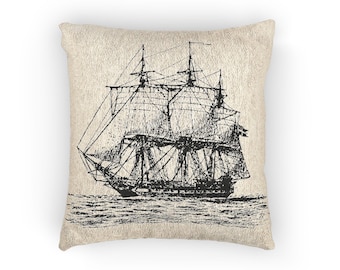 May include: A square pillow with a beige background featuring a black and white illustration of a tall sailing ship on the water. The ship has multiple masts and sails, with intricate line details. The pillow has a textured appearance.