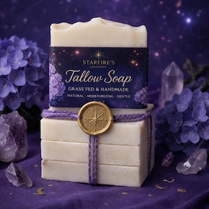 May include: A stack of handmade tallow soap bars, wrapped with purple twine and a gold seal. The top bar features a label with the text "Starfire's Creations Tallow Soap". The background includes purple hydrangeas and crystals, creating a natural, spa-like aesthetic.