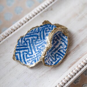 May include: A blue and white ceramic shell with gold accents. The shell is decorated with a geometric pattern.