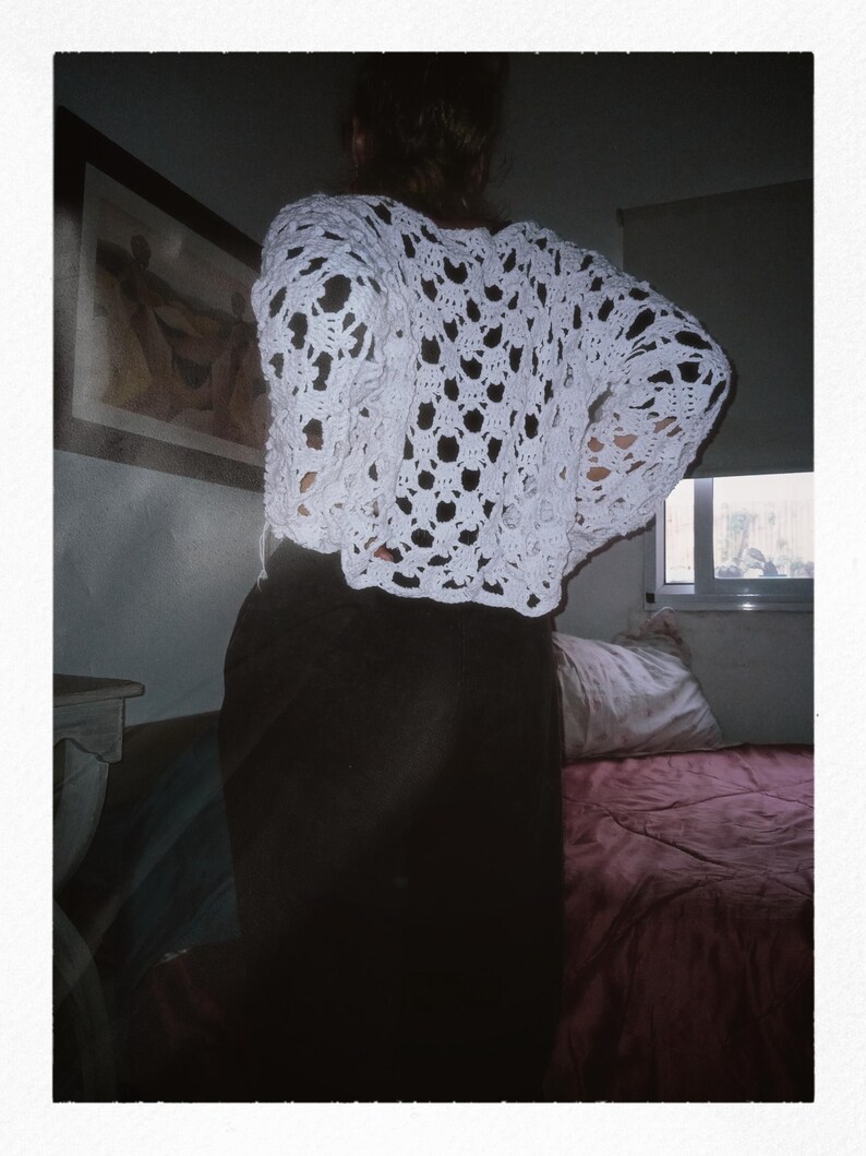 May include: A white crocheted top with a loose, open-weave design. The top has a relaxed fit and a slightly cropped length.