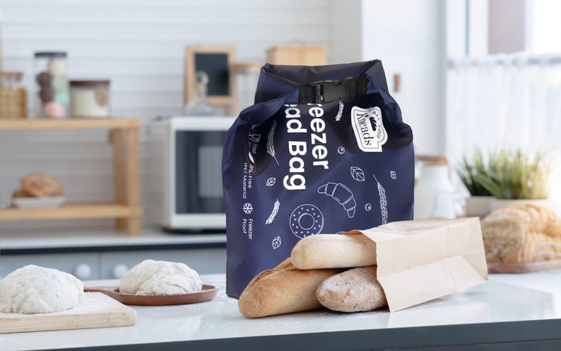 Puede incluir: Una bolsa de congelador azul con el texto "Freezer Bread Bag" y un logotipo que dice "Bread's". La bolsa est&aacute; llena de barras de pan y una bolsa de papel marr&oacute;n.