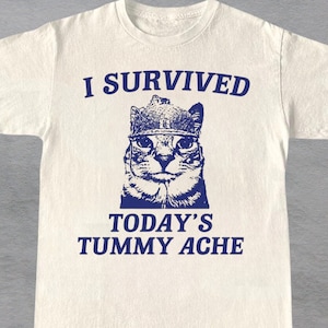 Ich überlebte das heutige Bauchschmerzen Shirt, lustiges Katzen-T-Shirt, Vintage Katzen-T-Shirt, Meme-T-Shirt, trendiges Unisex-T-Shirt, Bauchschmerzen-Überlebender-T-Shirt