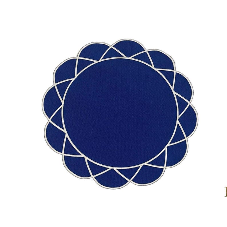 Top view of gather navy blue placemat with white embroidery, scalloped edge, and round flower design