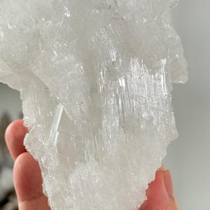 Puede incluir: Un gran grupo de cristales blancos translúcidos que presenta numerosas formaciones minerales afiladas, dentadas y alargadas. La estructura muestra una superficie compleja y multifacética con diversos grados de claridad y un aspecto brillante.