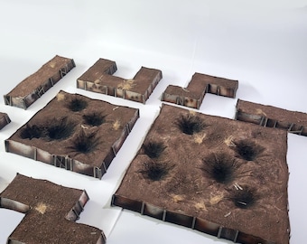 Pode incluir: Um conjunto de peças de terreno de plástico marrom e cinza para jogos de guerra. As peças são em forma de trincheiras e crateras, e são projetadas para representar um campo de batalha.