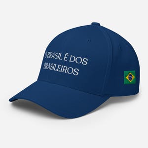 Puede incluir: Gorra de béisbol azul marino con texto bordado en blanco "O BRASIL É DOS BRASILEIROS". La gorra tiene un pequeño parche de la bandera brasileña en el lateral. Tiene una visera curva.