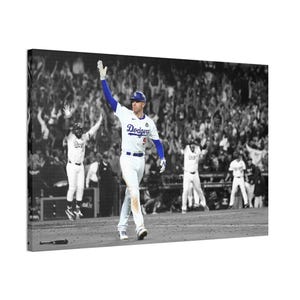 以下が含まれることがあります： ドジャースのユニフォームを着た野球選手が、勝利を祝って腕を上げている白黒のキャンバスプリント。選手は青い袖と背番号5の白いジャージを着ています。背景には歓声が上がる観客がいます。