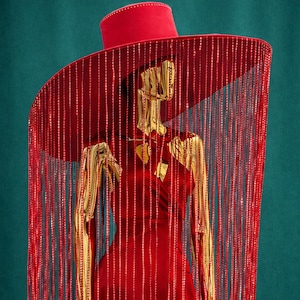 Chapeau tendance rouge couture avec franges, casque dramatique à large bord, chapeau éditorial haute couture, accessoire de créateur pour festival