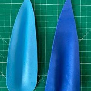 May include: Two blue paper cutouts on a green grid background. One is a teardrop shape, and the other is a triangular shape. The teardrop is a gradient of light to dark blue. The triangle is a solid, darker blue.