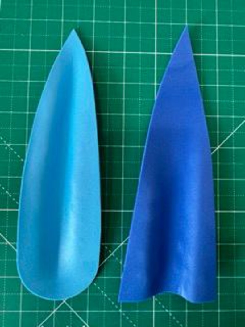 May include: Two blue paper cutouts on a green grid background. One is a teardrop shape, and the other is a triangular shape. The teardrop is a gradient of light to dark blue. The triangle is a solid, darker blue.